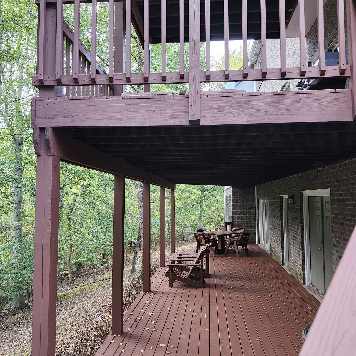 The lower level of the same deck, looking along freshly stained boards to a table and chairs beneath the deck above