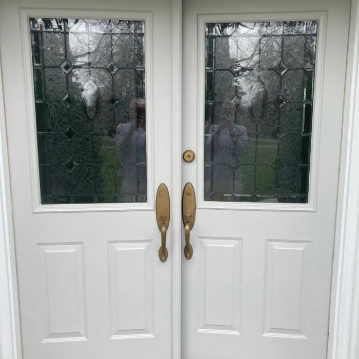 Double front doors refinished in satin white, with the leaded glass and brass handles cleaned up
