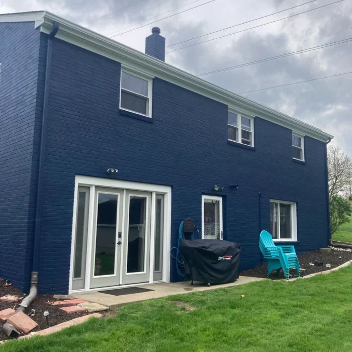 The finished house: brick painted deep navy with white trim and gutters