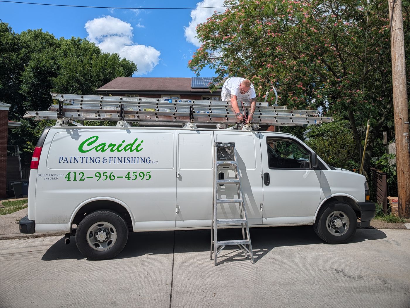 A Caridi Painting crew member strapping extension ladders onto the roof rack of the company van
